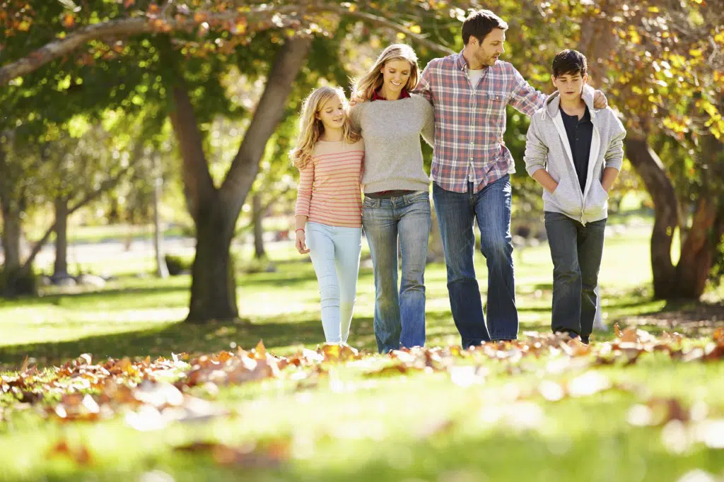 Family Walking Through Autumn Woodland